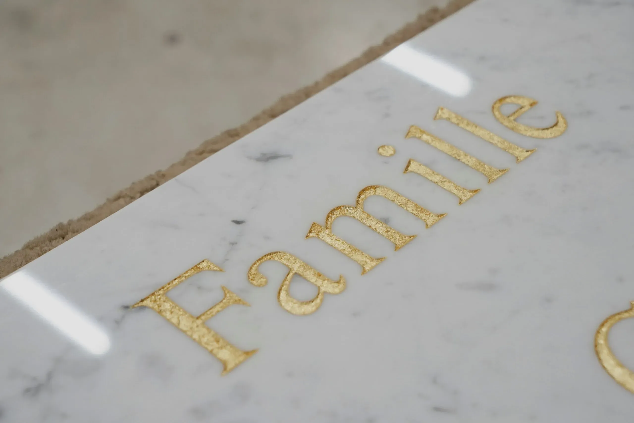 Gravure dorée réalisée à la feuille d'or sur une plaque en marbre blanc.